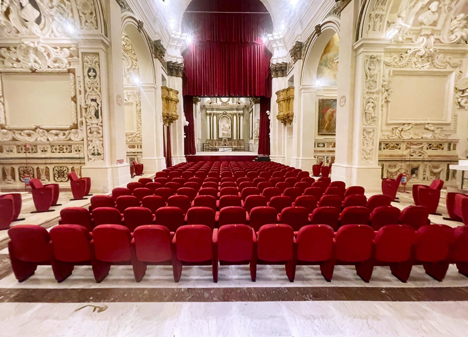Interno del Teatro San Filippo a L'Aquila dopo il restauro con poltrone per teatro e navata centrale